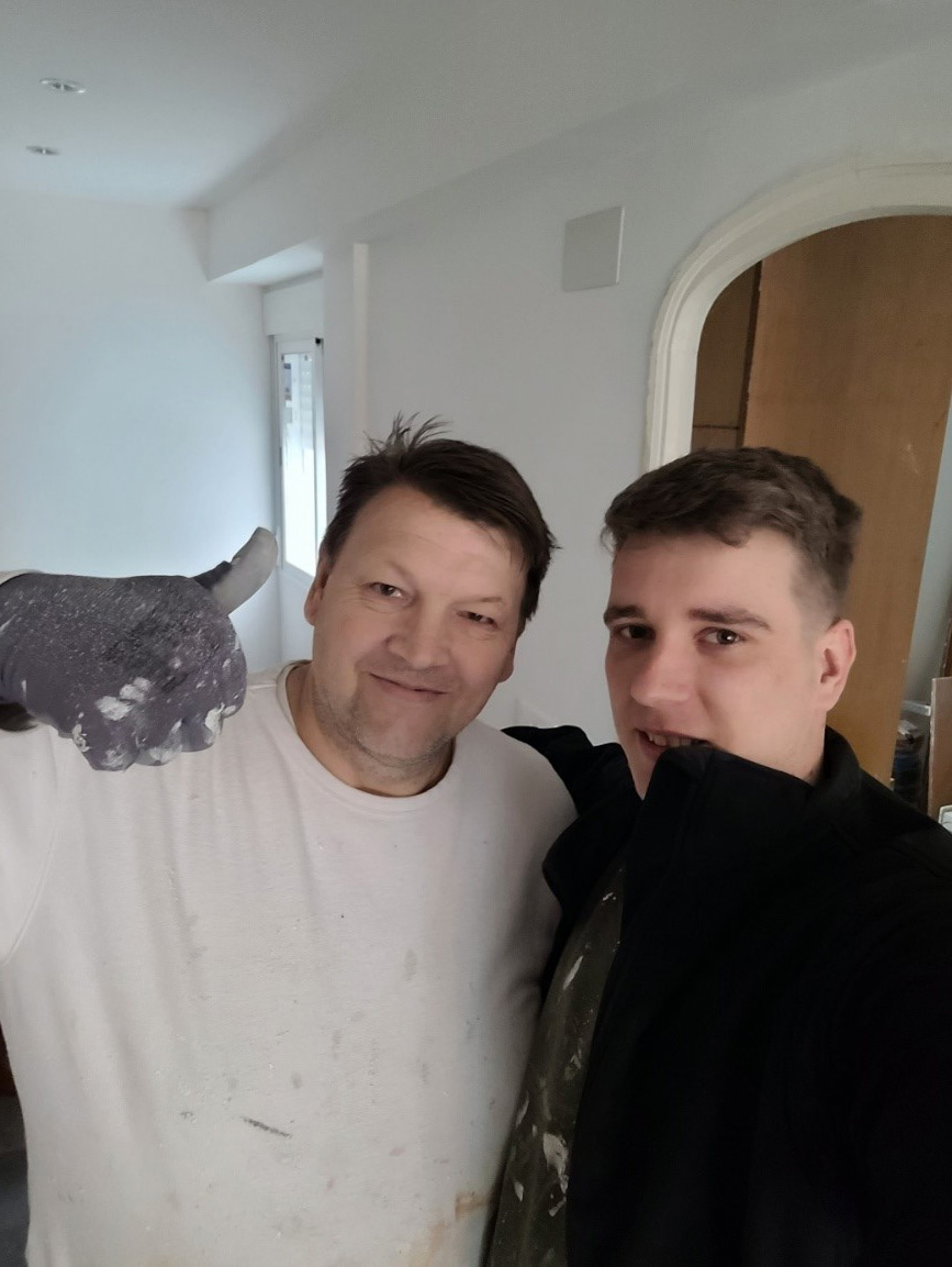 Zwei Maler stehen vor frisch gestrichenen Wänden